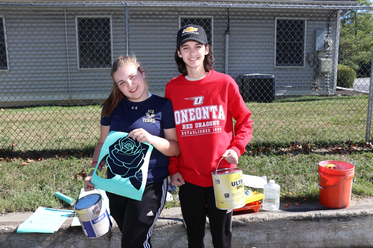 Students stand with painting equipment.