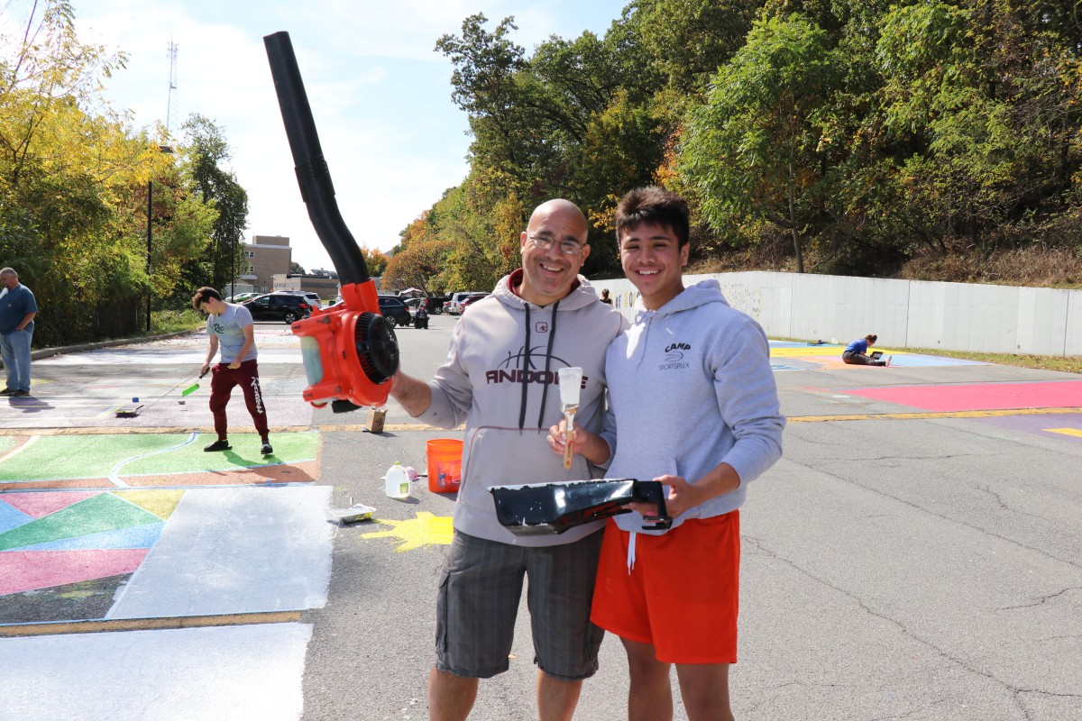 Student and helper pose with painting equipment.