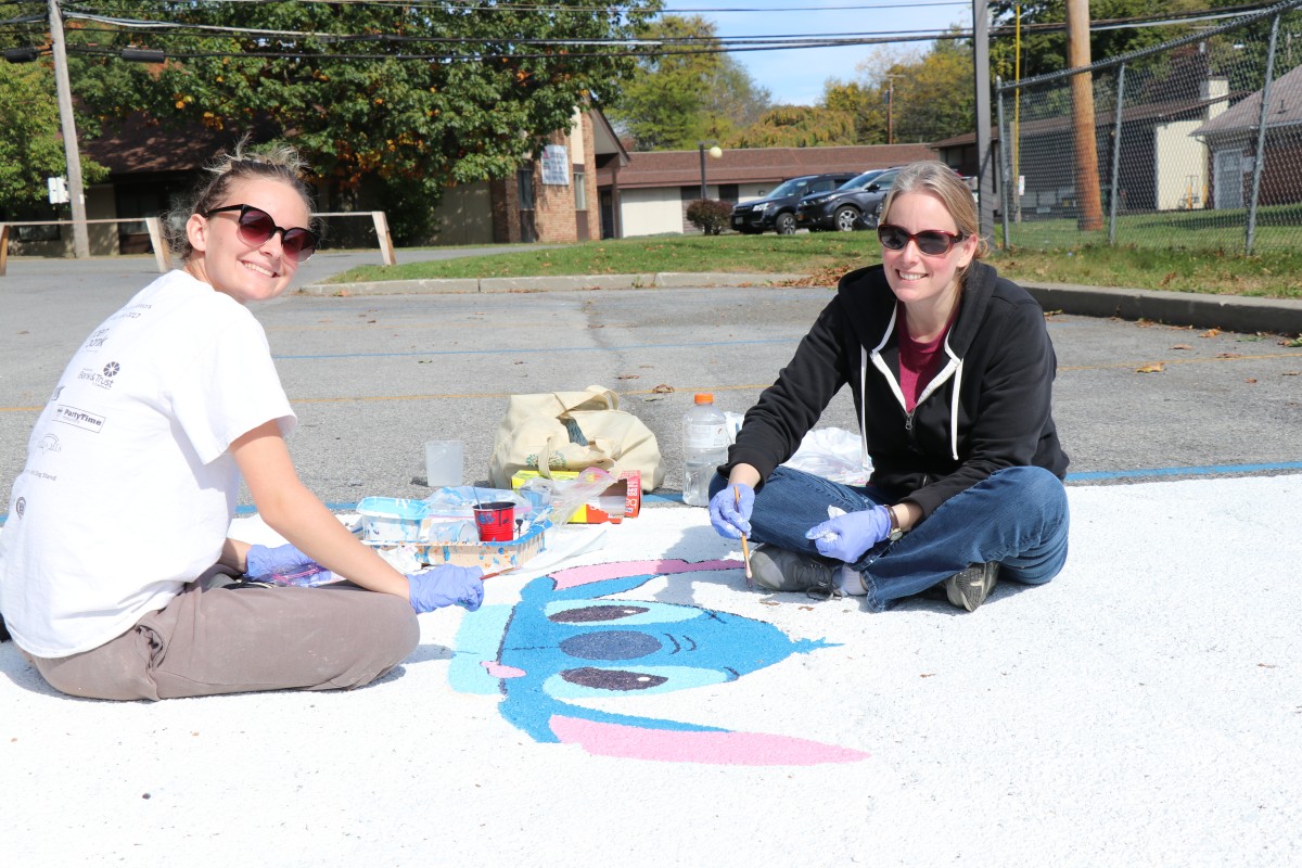 Student and helper painting parking spot.