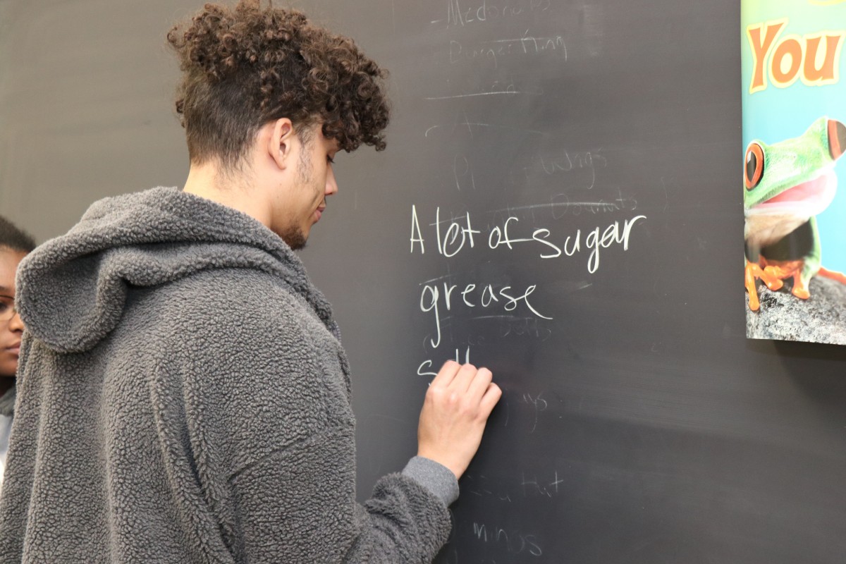 Student writing list on chalkboard.