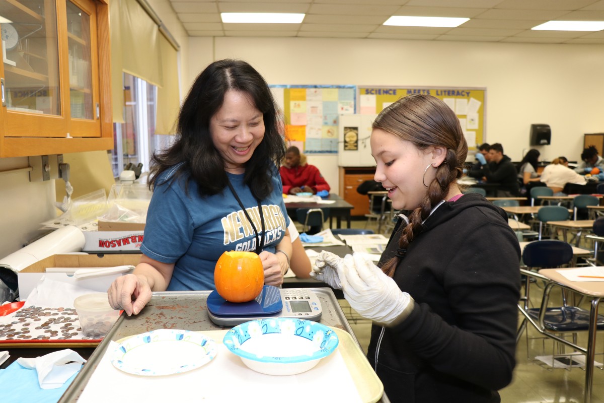 Teacher assisting student weighing pumpkin contents.