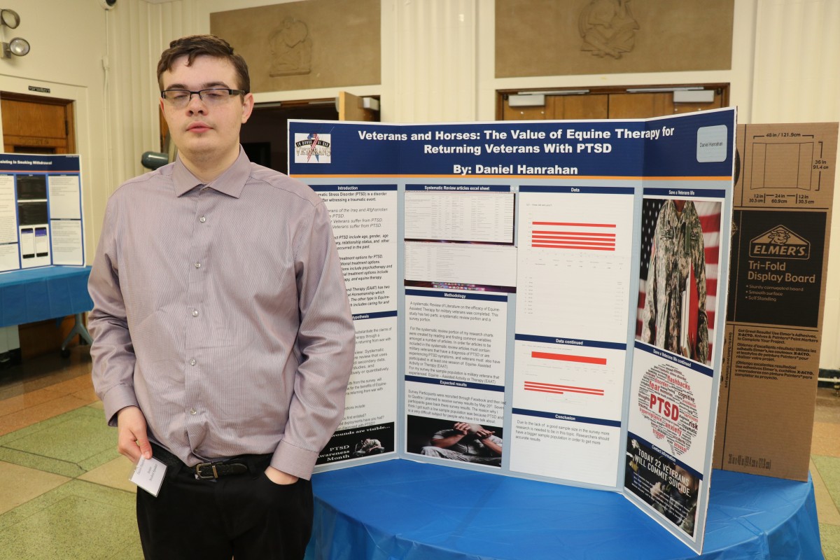 Student stands by post presentation.