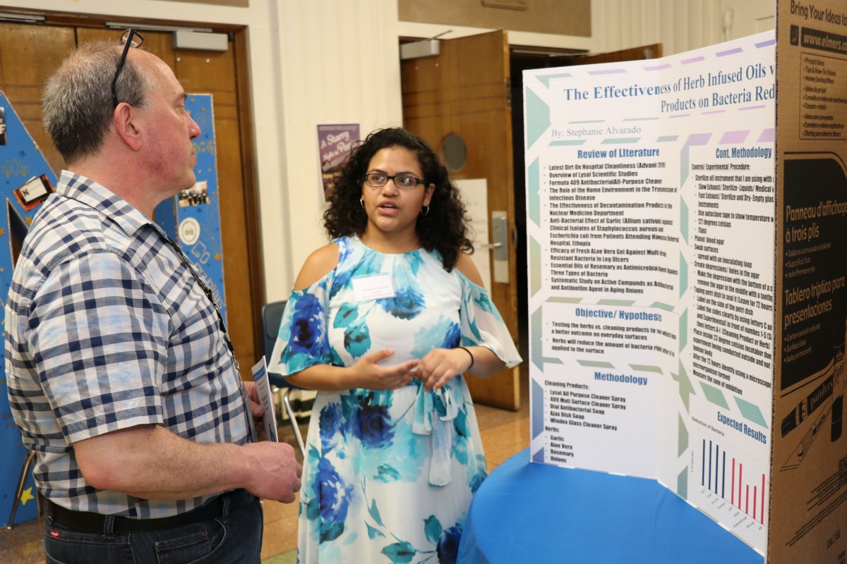 Student explains research at poster presentation.