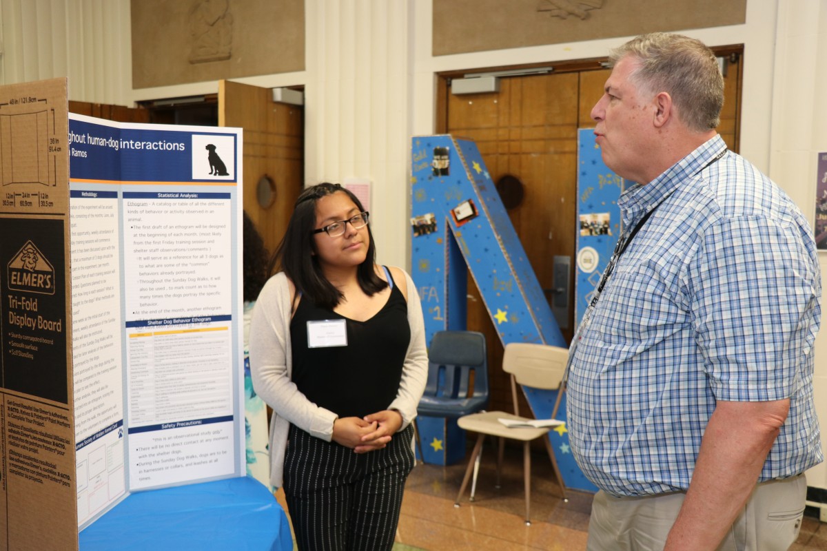 Student explains research at poster presentation.
