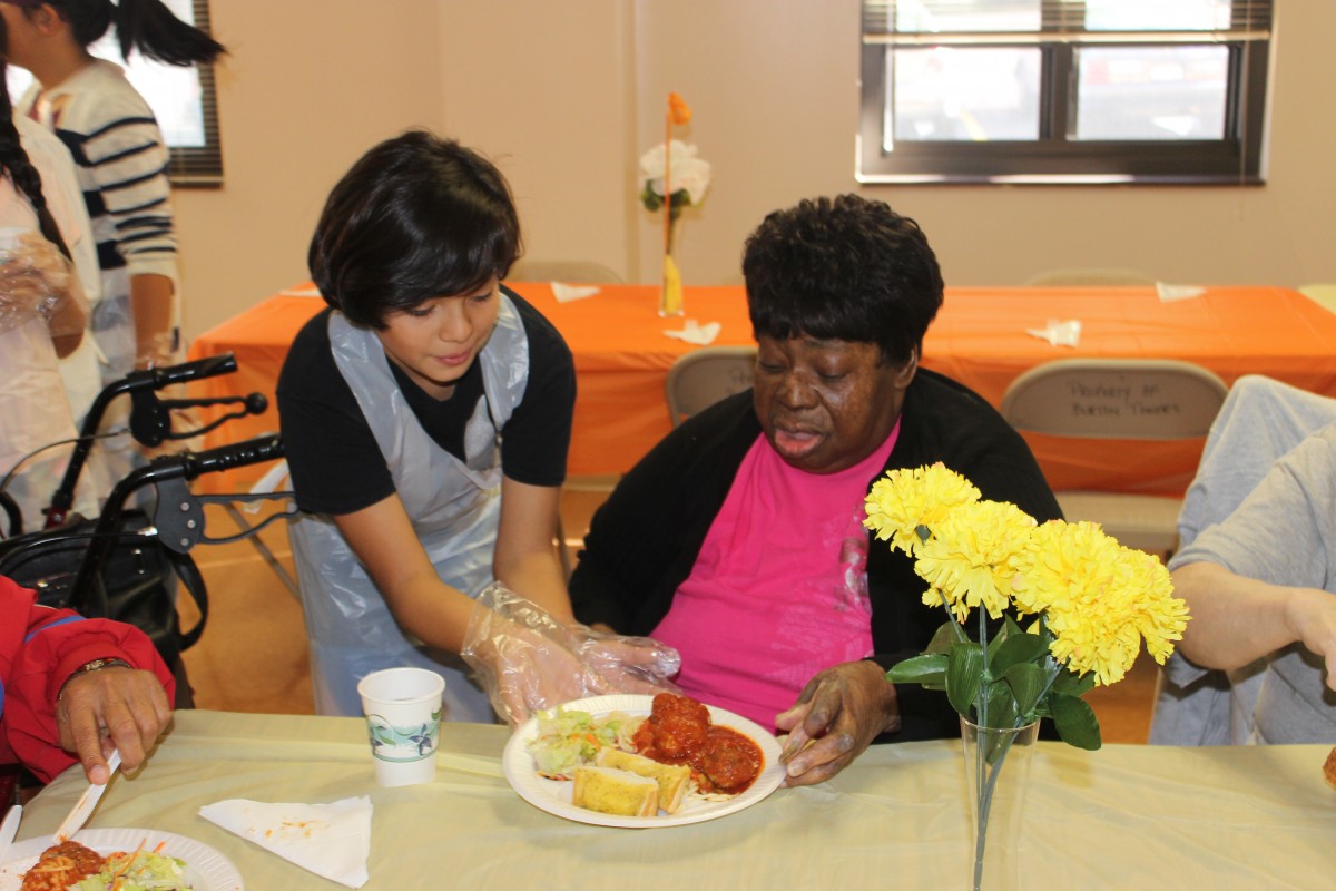 Student serving food to resident.