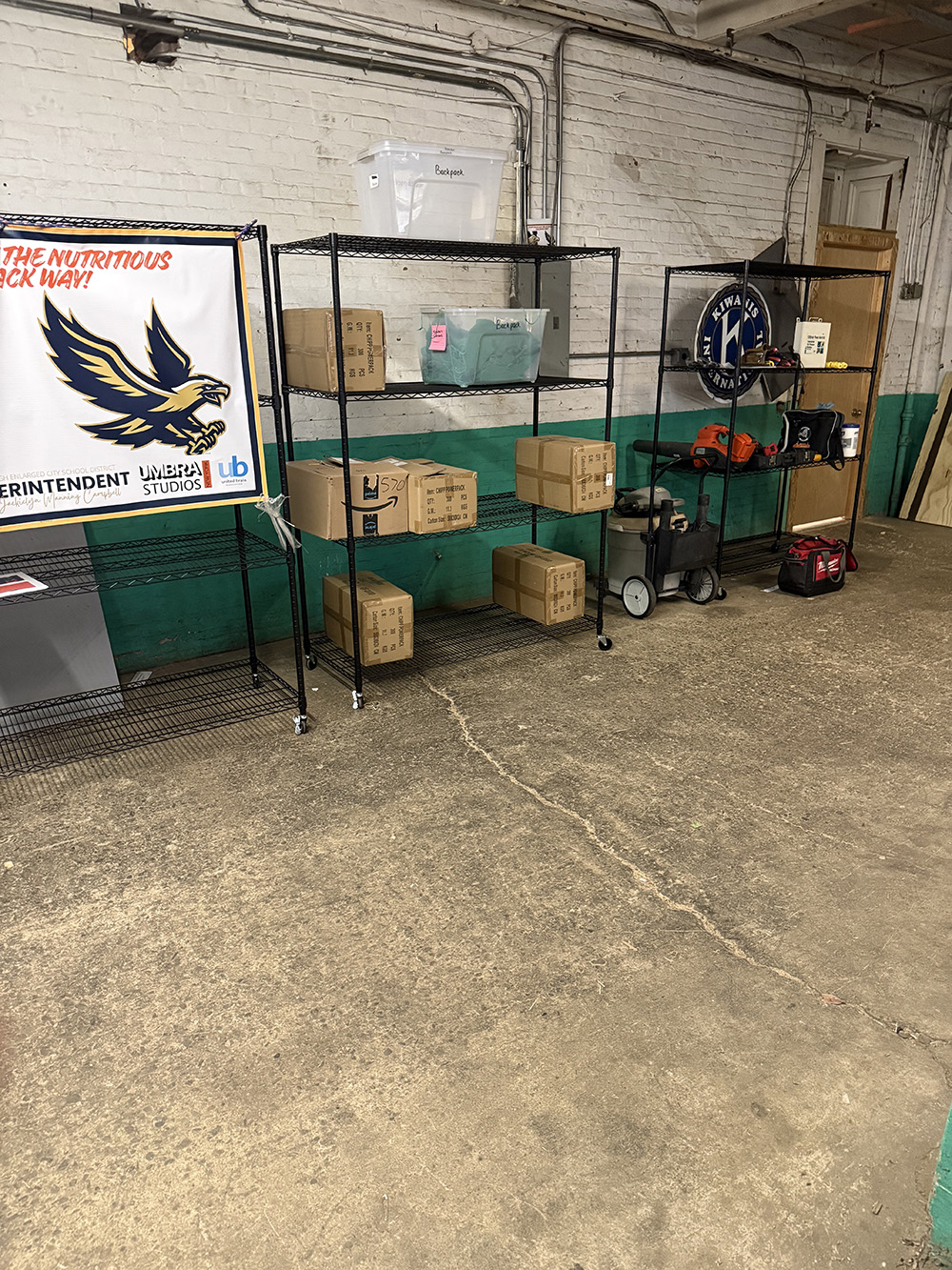 Shelving units hold boxes and storage bins in a supply room.